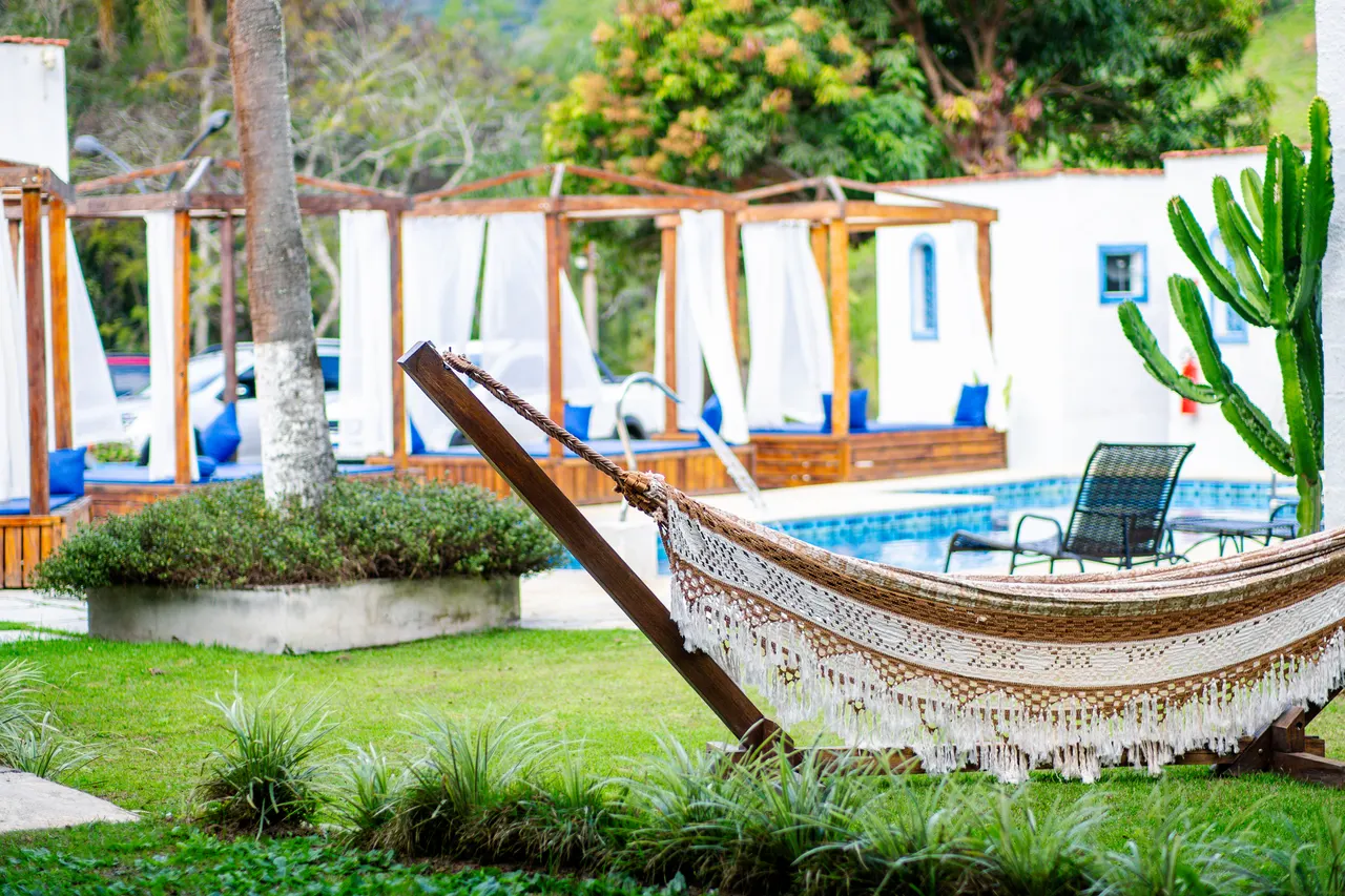 Rede no jardim com as cabanas e a piscina ao fundo