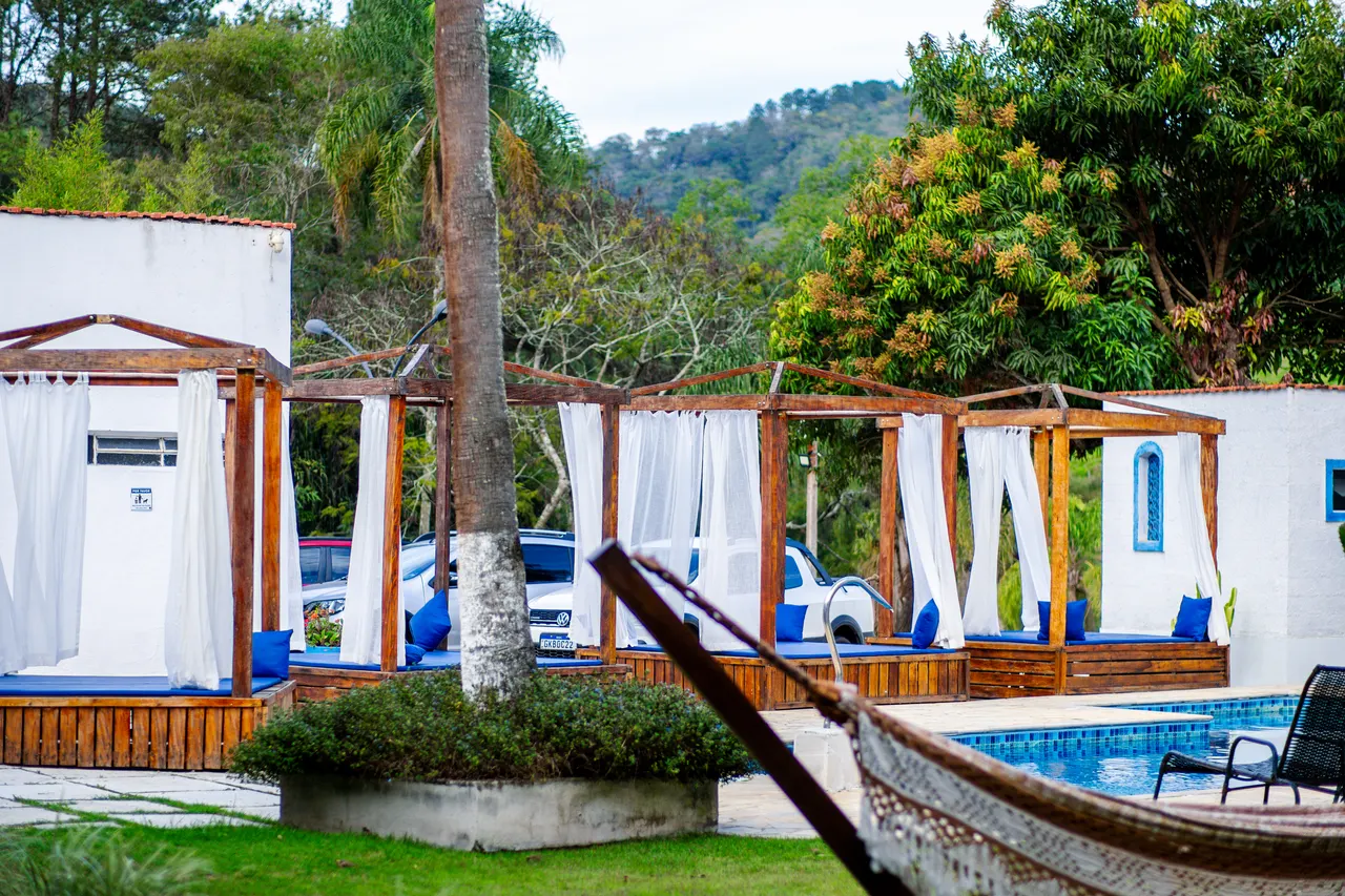 Cabanas, rede e piscina em meio ao verde